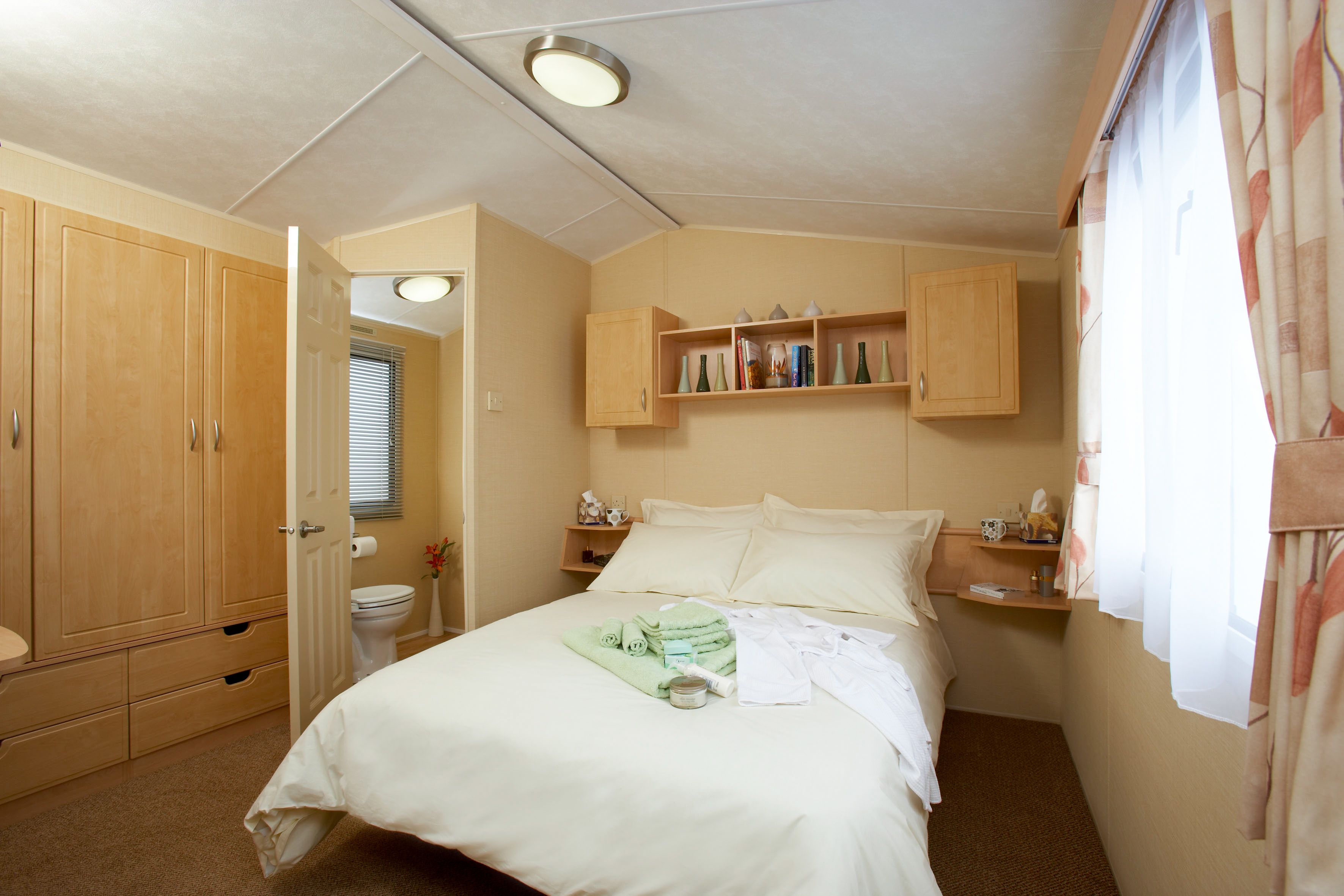 Ein Schlafzimmer mit einem Bett, einem Holzschrank und einem Regal mit Pflegeprodukten.