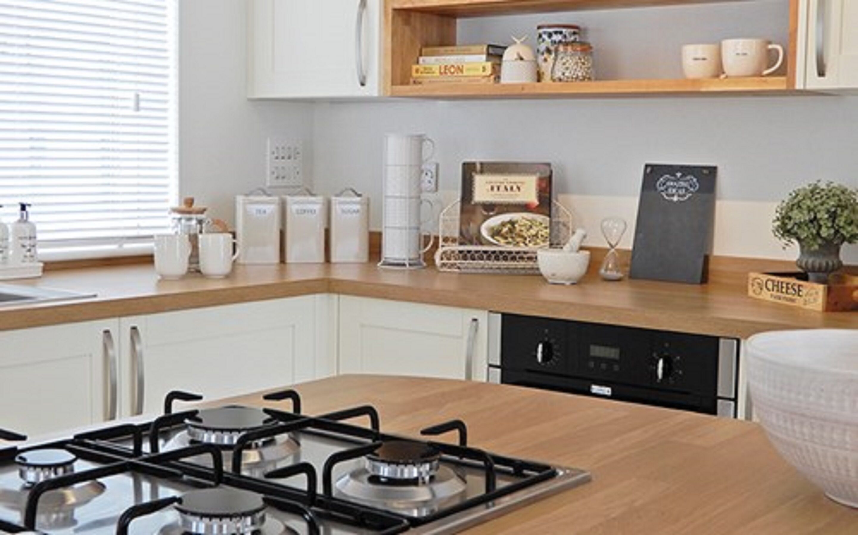Una cocina moderna con estufa a gas, armarios blancos y encimera de madera.