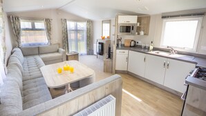 A modern RV interior with a living area, kitchenette, and dining space. - The Lakes Rookley Holiday Park (Ventnor)