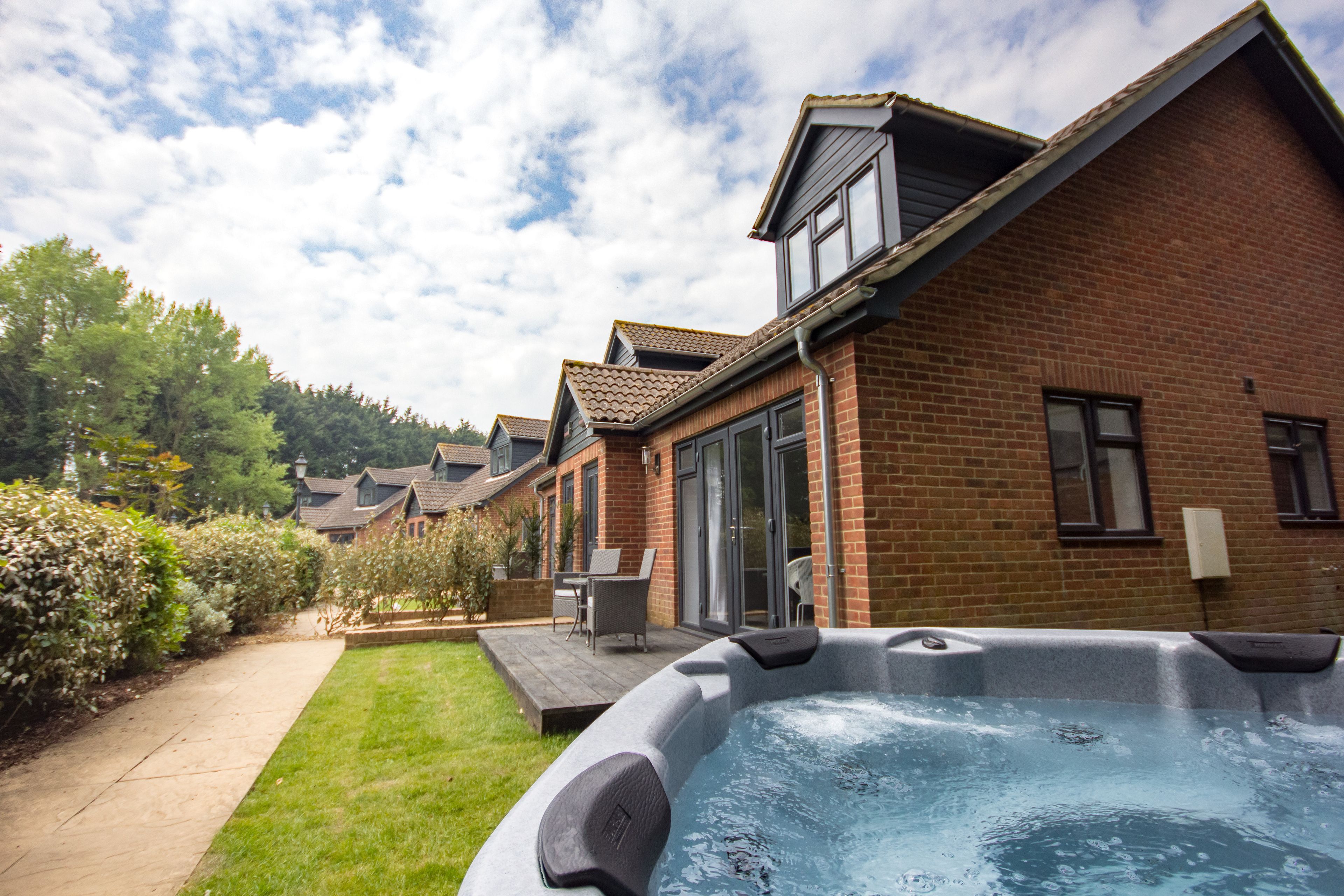 A residential property with a brick house, a hot tub, and a patio with outdoor furniture.