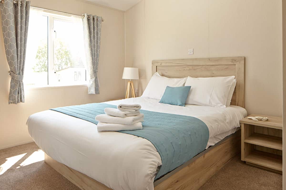 A neatly made bed with a blue and white bedding set, a bedside lamp, and a wooden nightstand.