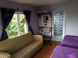 A room with a sofa, two beds, a wooden dresser, a mirror, and a window with curtains. - Hostal Nueva Vida (Ciénaga de Zapata)