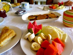 A dining table with plates of food, including pancakes, fruit, and a slice of cake. - Hostal Nueva Vida (Ciénaga de Zapata)