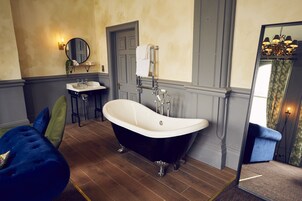 A bathroom with a freestanding bathtub, a sink, and a mirror.
