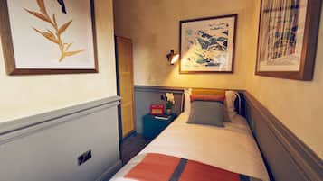 A hotel room with a bed, a nightstand, a lamp, and framed artwork on the walls.