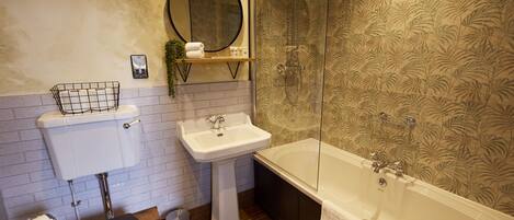 Et badeværelse med toilet, håndvask og badekar.