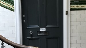 A black door with a nameplate reading "DUNBAR" and a small mailbox below it. - Silver Lining - Meadows Apartments (Edinburgh)