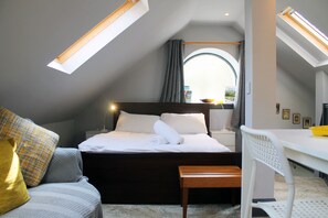 Um quarto com cama, mesa de cabeceira e escrivaninha com cadeira.