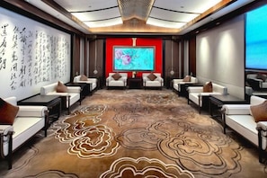 A conference room with a carpeted floor, white sofas, and a large screen at the front.