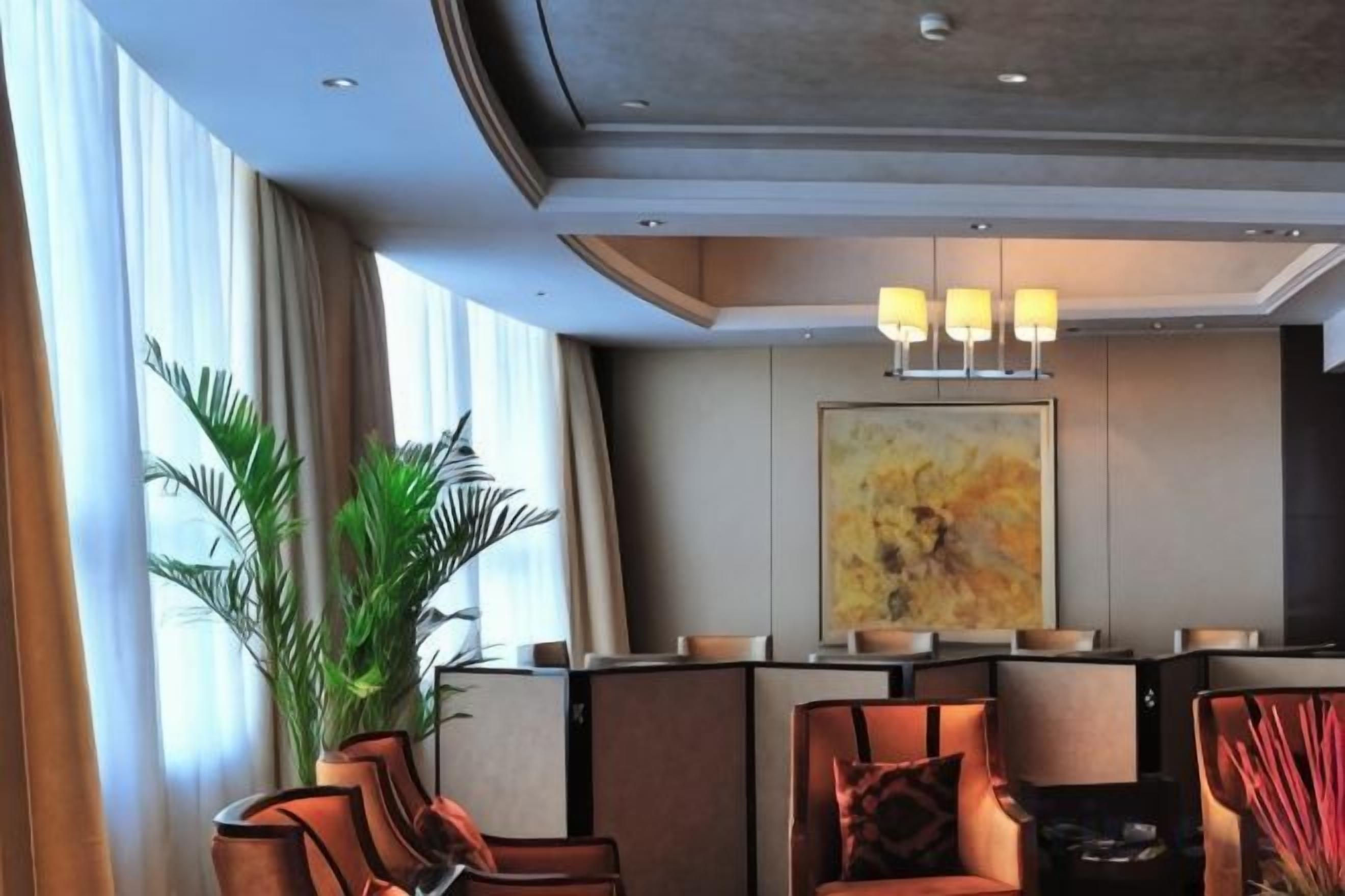 Um saguão de hotel com assentos, uma janela grande e uma pintura na parede.