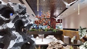 A reception area with a modern design, featuring a large rock sculpture, a reception desk, and a seating area with cushions.