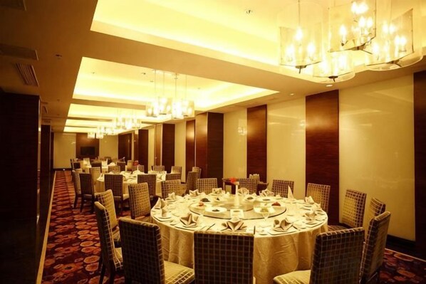 A conference room with round tables, chairs, and chandeliers.