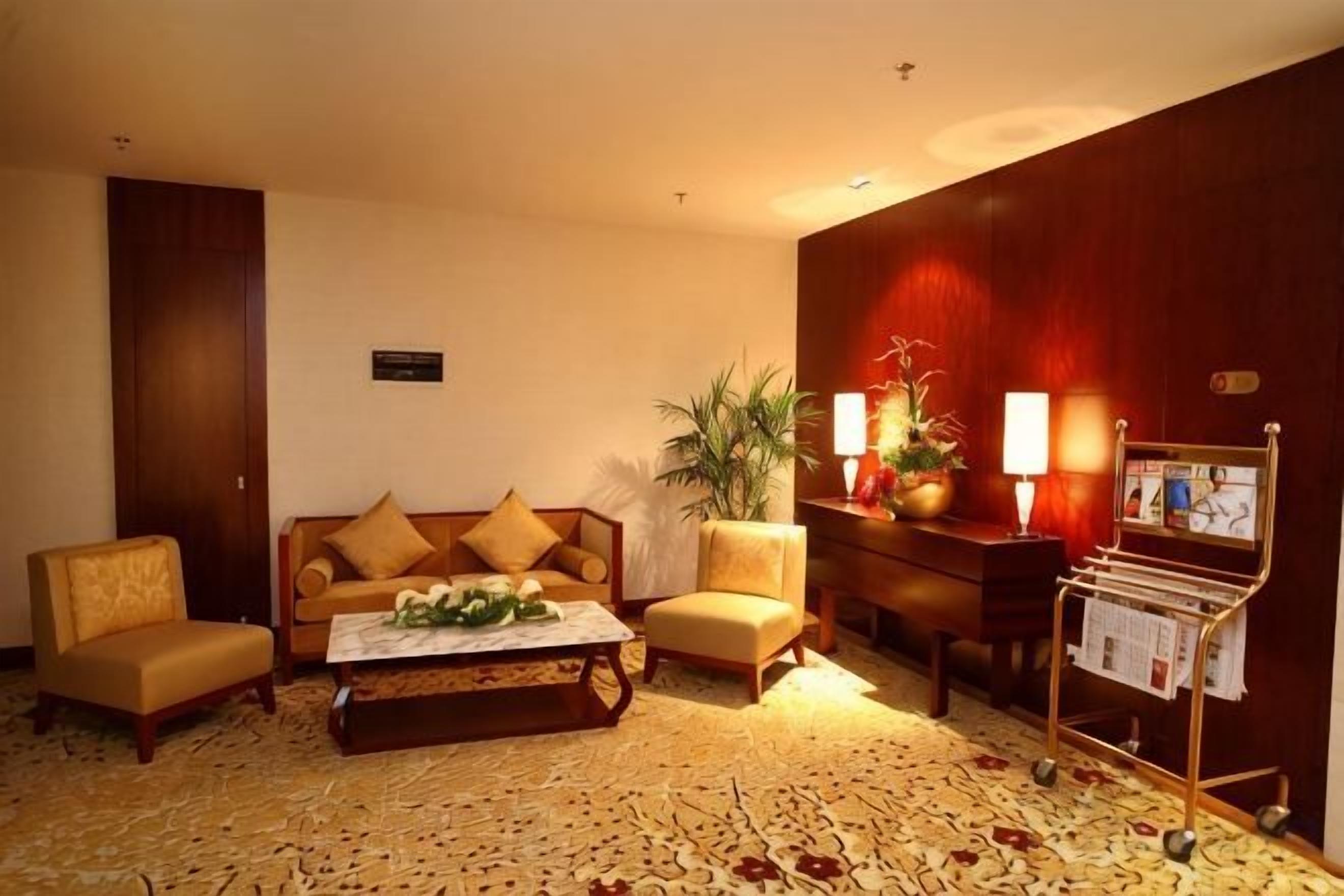 A hotel lobby with a sofa set, a coffee table, a magazine rack, and a potted plant.