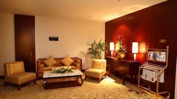A hotel lobby with a sofa set, a coffee table, a magazine rack, and a potted plant.