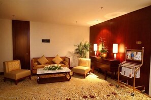 A hotel lobby with a sofa set, a coffee table, a magazine rack, and a potted plant.