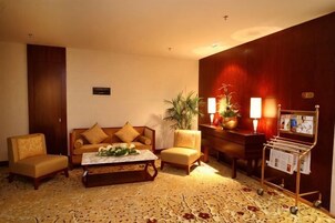 Un hall de hotel con un conjunto de sofás, una mesa de centro, un atril para revistas y una planta en maceta.