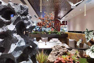 A modern lobby with a rock sculpture, a reception desk, and a seating area with plants.