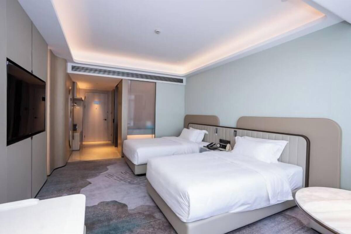 Ein Hotelzimmer mit zwei Betten, einem Fernseher, einem Schreibtisch und einem Badezimmer.