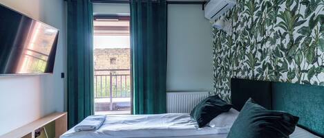 Une chambre d’hôtel avec un lit, une télévision, une fenêtre avec des rideaux et un radiateur.