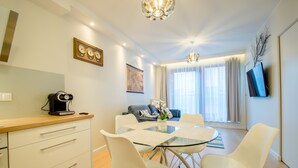 A modern dining area with a glass table, white chairs, and a coffee machine.