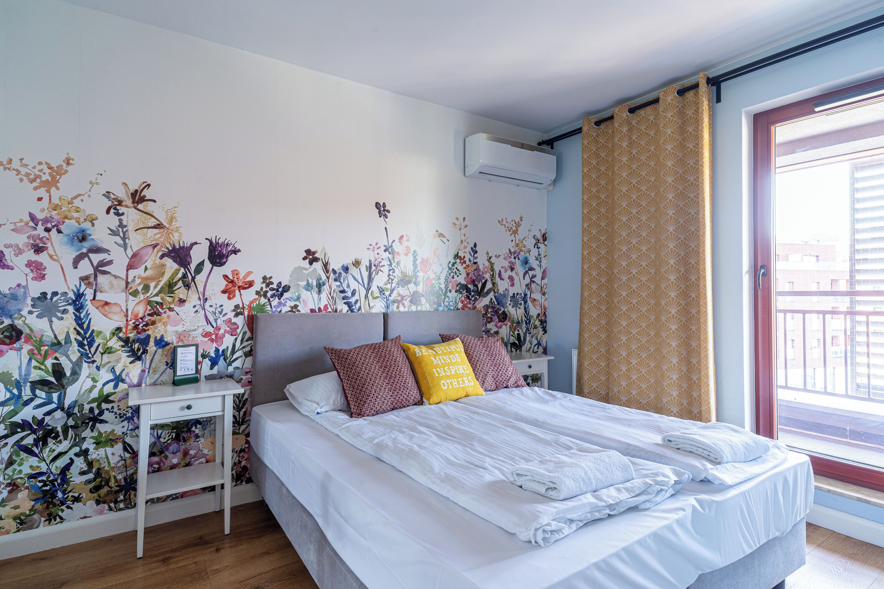 Una camera da letto con un murale floreale, un letto con biancheria bianca e un comodino con una lampada.