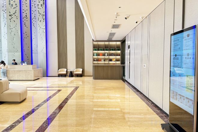 Un hall de hotel con una recepción, zona de estar y un panel informativo digital.
