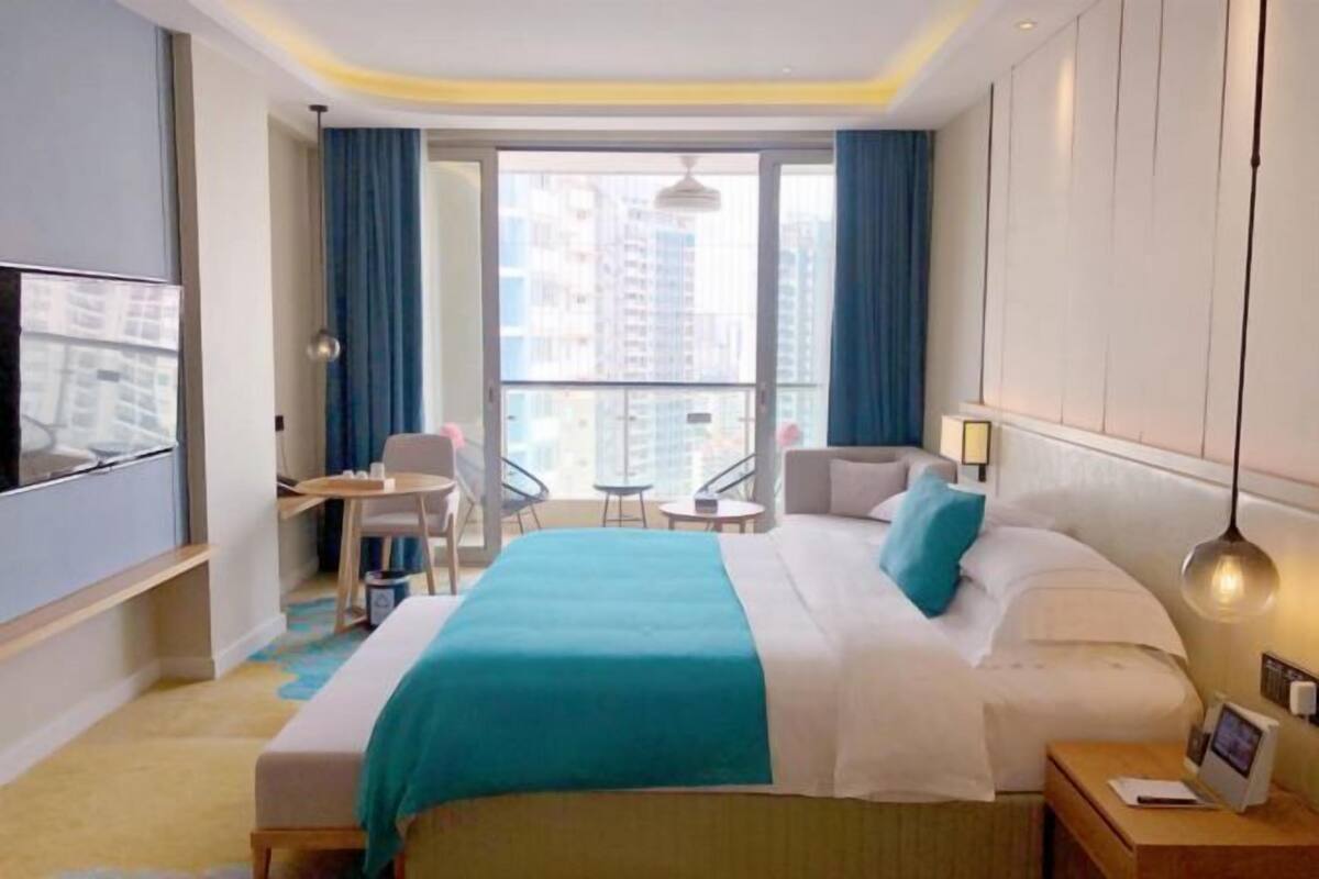 Une chambre d’hôtel avec un lit, un bureau, une chaise, une petite table et un téléviseur.