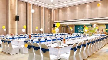 A banquet hall with round tables, white chairs, and blue sashes.