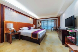 Une chambre d’hôtel avec un grand lit, une télévision, un bureau et une vue sur l’extérieur.