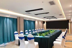 A conference room with a long table, white chairs with blue sashes, and a projector screen. - Nanning Jingdu International Hotel (Nanhu Park Binhu Road Metro Station) (Nanning)