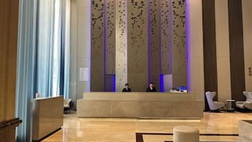 Una zona d'entrada amb disseny modern, que inclou un taulell de recepció, una zona de seients i panells decoratius a la paret.
