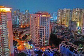 Un edificio de gran altura con varios pisos, rodeado de otros edificios altos, lo que indica una zona urbana densamente poblada.
