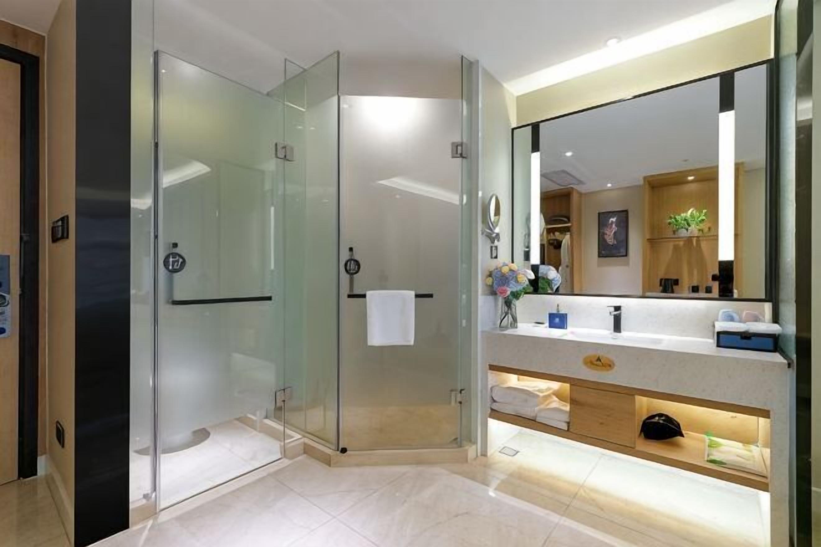 A modern bathroom with a glass shower enclosure, a vanity with a mirror, and a towel rack.