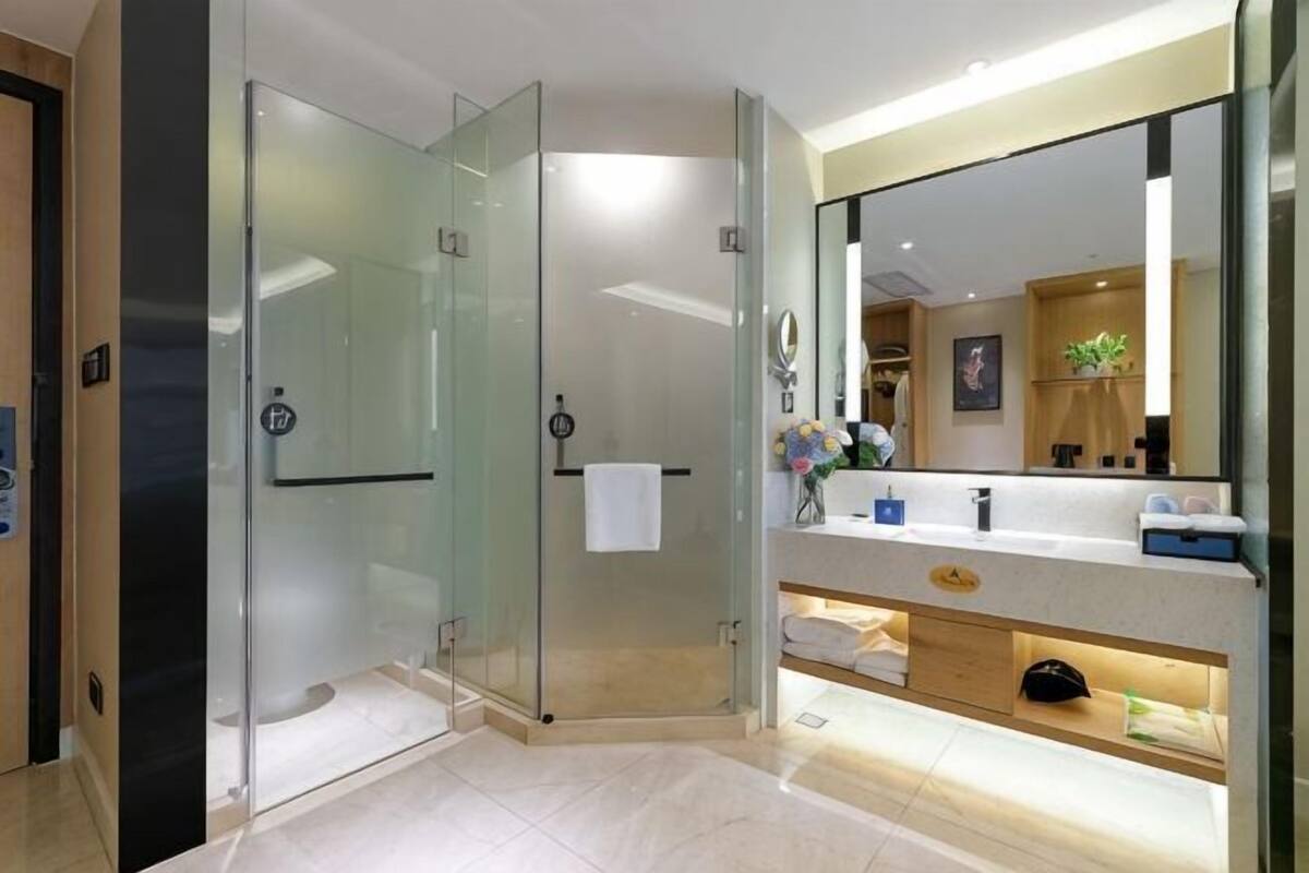 Une salle de bain moderne avec une douche à parois de verre, un meuble-lavabo avec un miroir et un porte-serviettes.