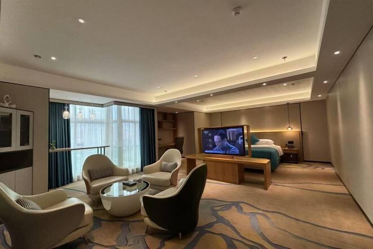 Une chambre d’hôtel moderne équipée d’une télévision, d’un coin salon et d’une grande fenêtre.