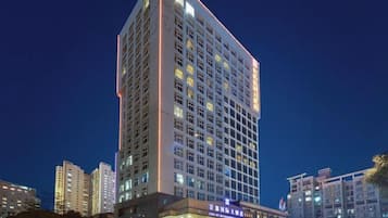 A high-rise hotel with multiple floors, a prominent entrance, and a well-lit facade.