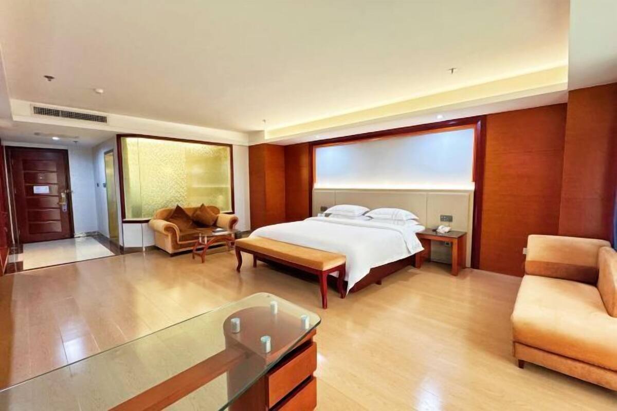 Une chambre d’hôtel avec un lit, un canapé, un bureau et une table basse en verre.