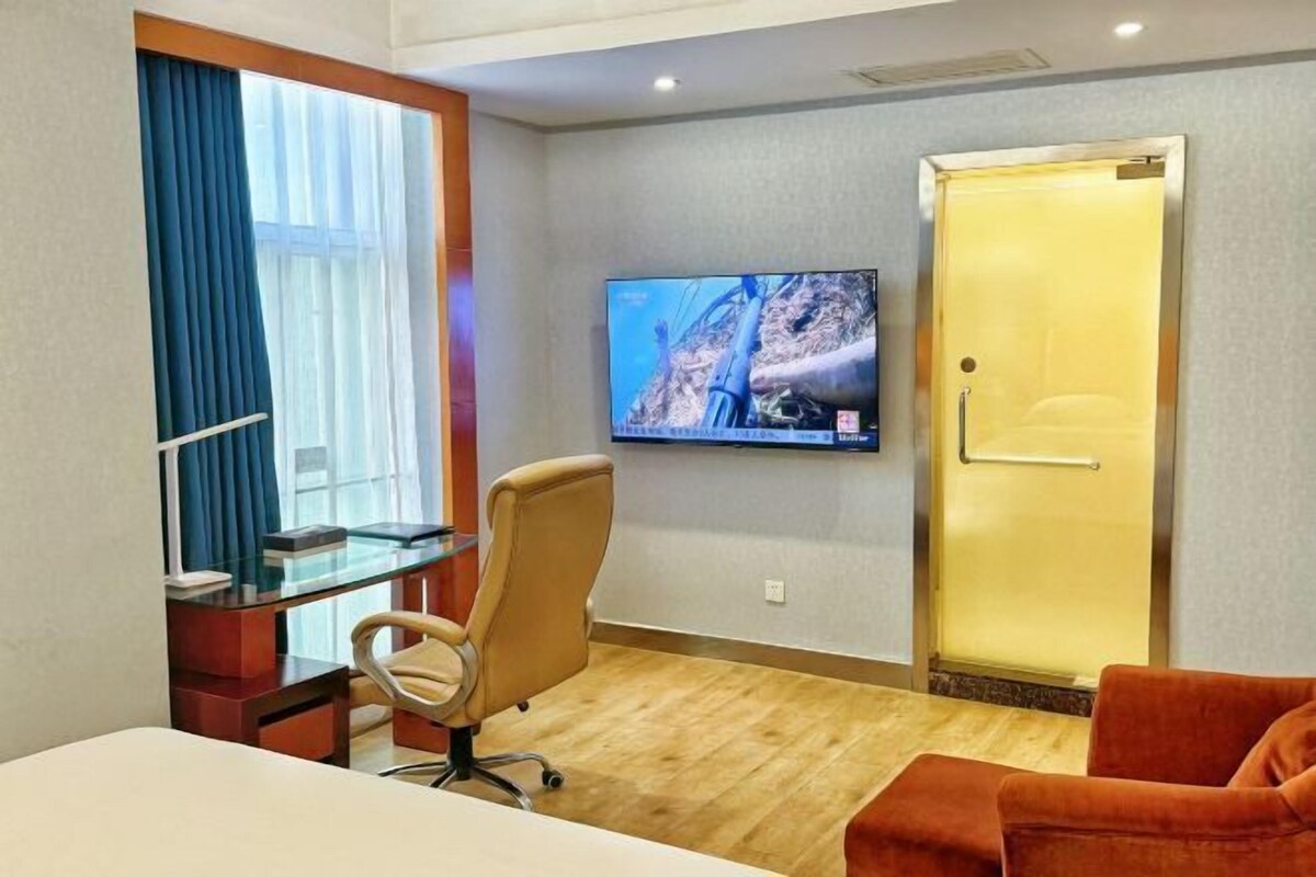 Une chambre d’hôtel comprenant un lit, un bureau avec une chaise, un téléviseur fixé au mur et une porte.
