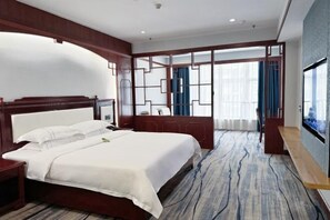 Une chambre d’hôtel avec un grand lit, une tête de lit en bois, un bureau et une télévision.