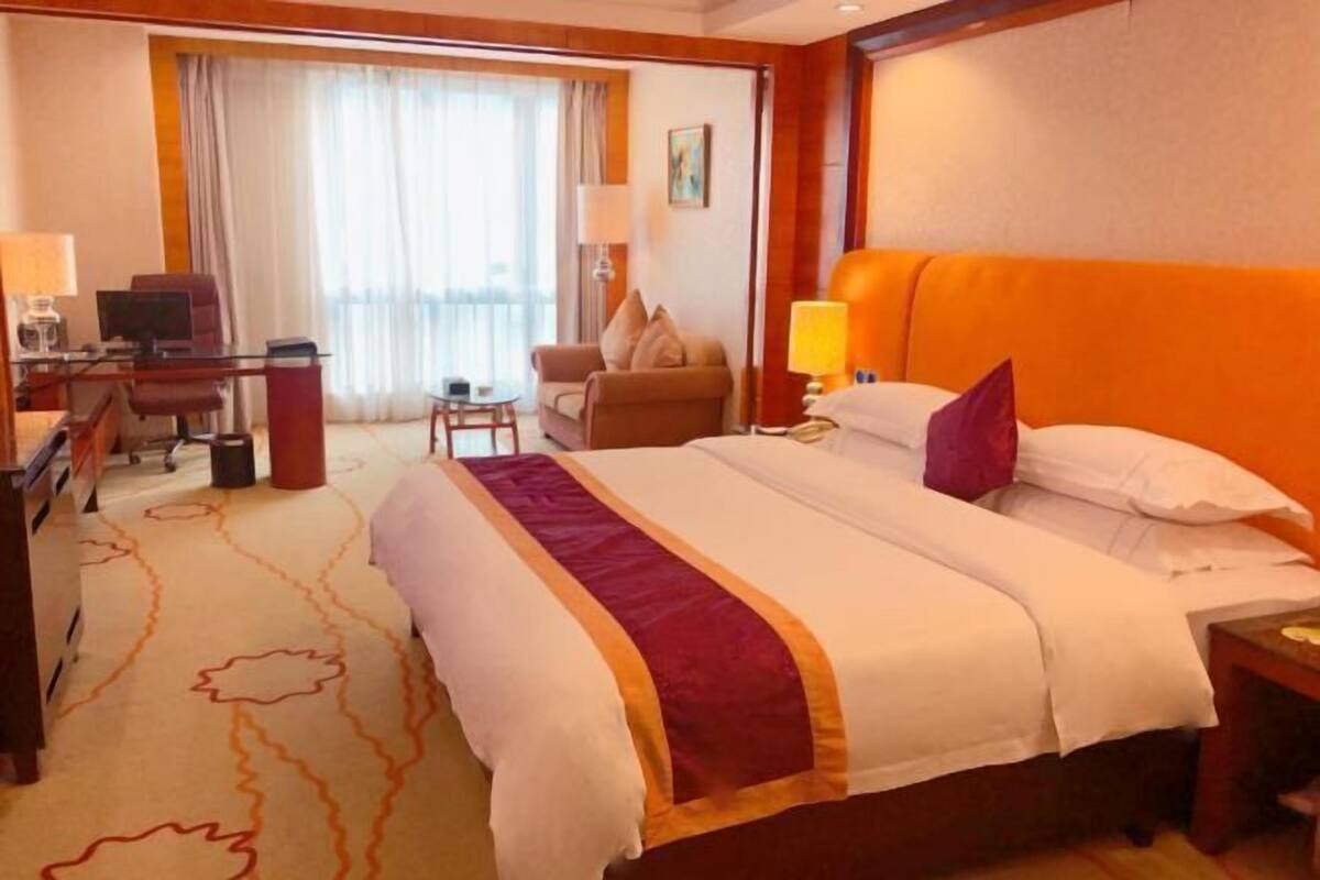 Une chambre d’hôtel avec un grand lit, un bureau avec un ordinateur, une chaise et une petite table.