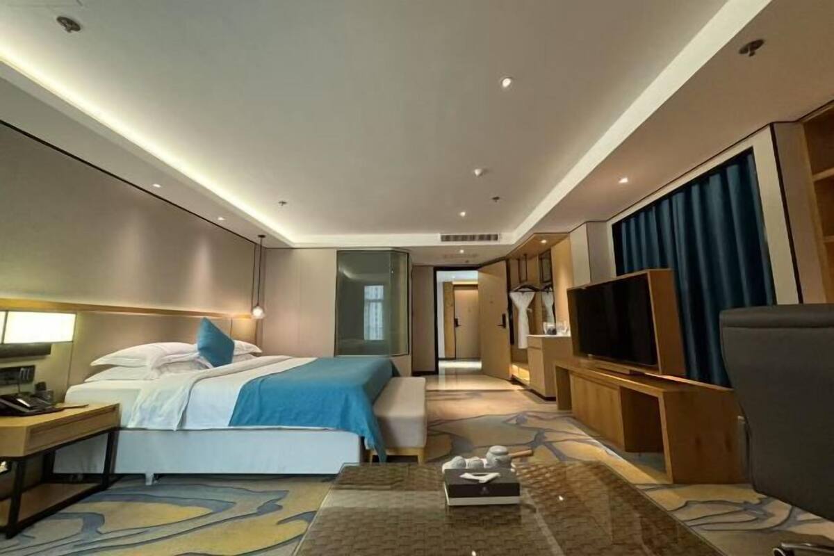 Une chambre d’hôtel comprenant un lit, une table de chevet, une télévision et un coin salon avec une table basse.