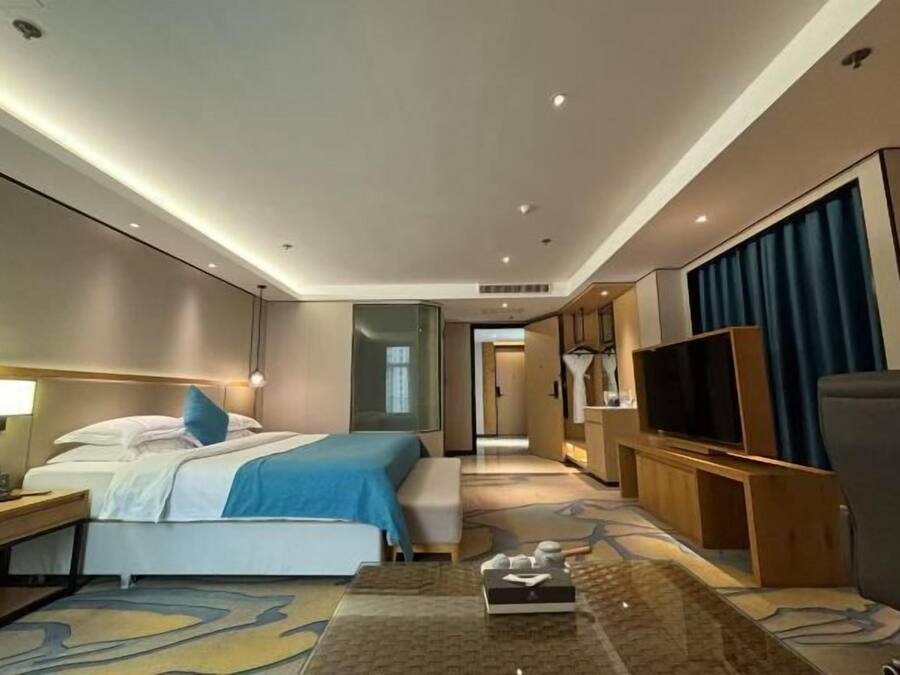 Una camera d'albergo con un letto, un comodino, una TV e un angolo salotto con tavolino.