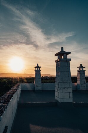 Auringonlaskunäkymä, jossa näkyy kaksi kivipilaria katolla.