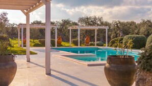 A pool area with a pergola, large vases, and lush greenery. - Masseria Torre Abate Risi (Fasano)