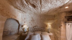 A stone-walled bedroom with a bed, two bedside lamps, and a nightstand. - Masseria Torre Abate Risi (Fasano)