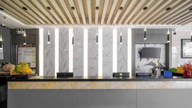 A reception area with a marble counter, pendant lighting, a flat-screen TV, and a wooden ceiling. - Nanning Shenxianju Hotel (Jiangnan Passenger Transport Terminal) (Nanning)
