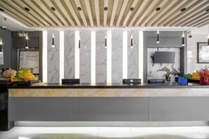 Un espace d’accueil doté d’un comptoir en marbre, de luminaires suspendus, d’un téléviseur à écran plat et d’un plafond en bois.