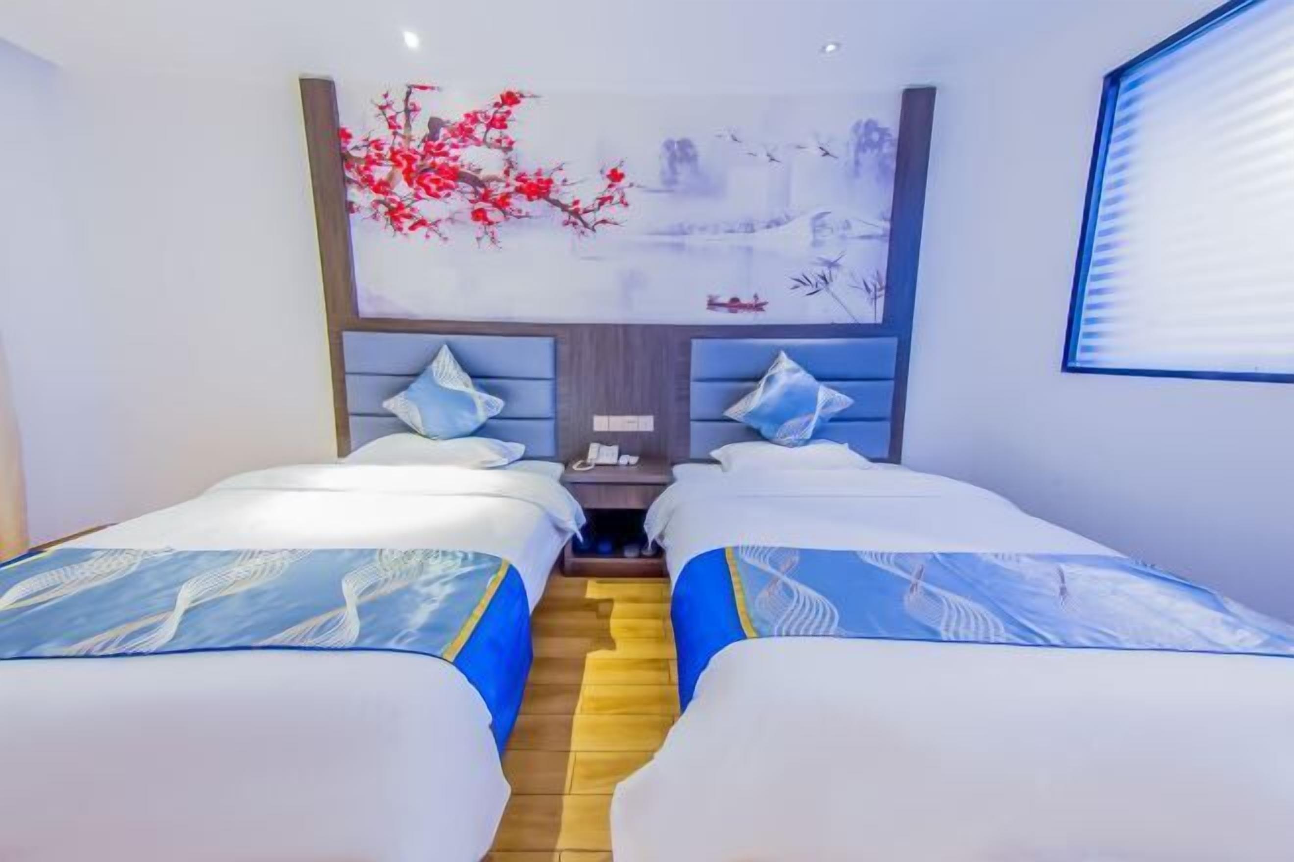 Ein Hotelzimmer mit zwei Betten, einem Nachttisch und einem Wandbild.