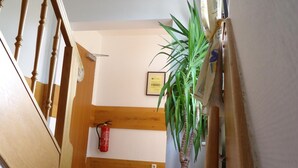 A staircase with wooden balusters, a potted plant, a fire extinguisher, and a framed certificate on the wall. - CityHotel Magdeburg (Magdeburg)