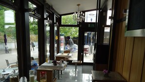An indoor dining area with tables and chairs, a chandelier, and large windows. - CityHotel Magdeburg (Magdeburg)
